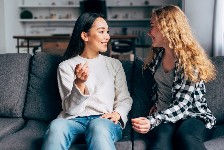 Two woman setting on a couch chatting