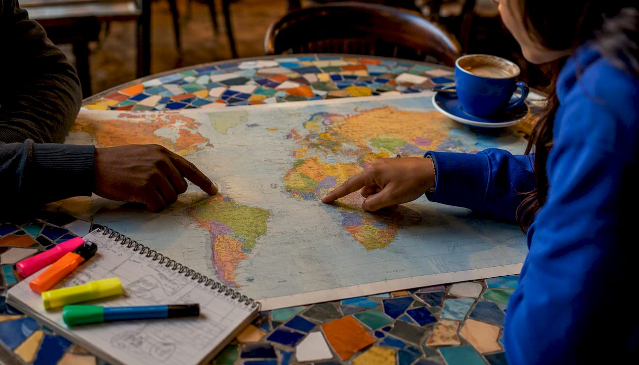 Hands pointing at Spanish-speaking countries on map