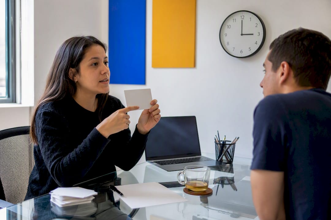 Tutor hands showing business Spanish flashcard
